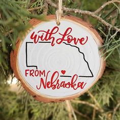 a wooden ornament hanging from a tree with the words, with love from nebraska