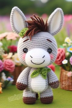 a crocheted stuffed animal with a green bow on it's head sitting in front of flowers