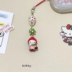 a hello kitty keychain hanging on a table next to some stickers and magnets