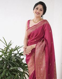 a woman in a pink sari standing next to a potted plant and smiling