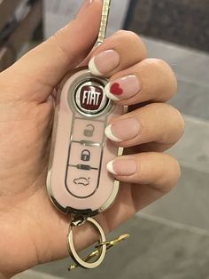 a woman holding a pink remote control keychain with fiat logo on the front