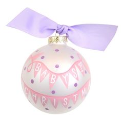 a baby's first christmas ornament with a purple ribbon on top and pink polka dots