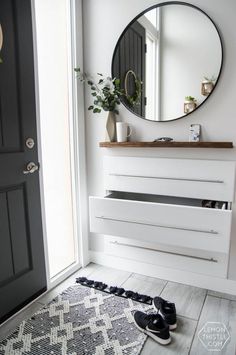 a black and white bathroom with a round mirror on the wall next to a pair of shoes