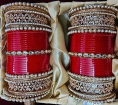 two red bracelets are sitting in a box with pearls and stones on the sides