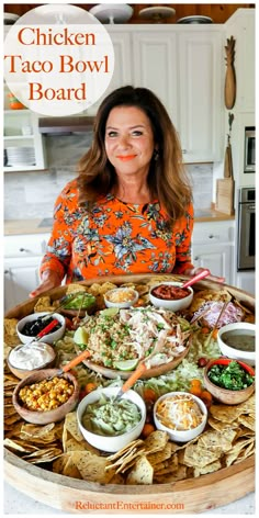 a woman standing in front of a platter filled with taco bowls and tortilla chips