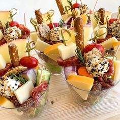 a wooden table topped with cups filled with different types of appetizers and toppings