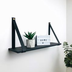 a shelf with some books and a potted plant on it next to a white wall