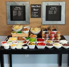 an assortment of food on a table with chalkboard menus behind it and two framed pictures