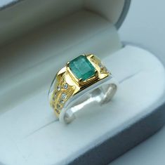 an emerald and diamond ring in a box