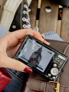 a person holding a cell phone in their left hand and sitting on a wooden bench