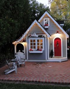 a small gray and white house with lights on the front door, porch and windows