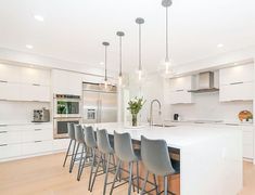 a kitchen with white cabinets and bar stools next to an island in the middle