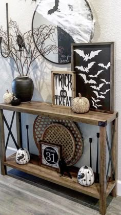 a wooden shelf with halloween decorations on it and two framed pictures hanging above the shelves