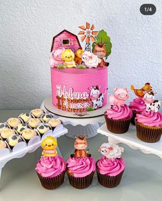 there are cupcakes on the table with pink frosting and farm animals around them