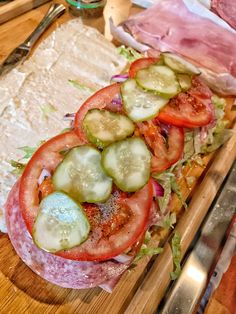 sliced tomatoes, cucumbers, and lettuce on a wooden cutting board