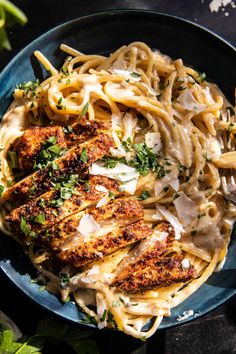 pasta with chicken and parmesan cheese in a blue bowl on a black table