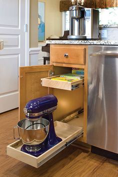 an open kitchen cabinet with a mixer and other items in the bottom drawer next to it