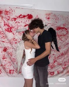 two people standing next to each other in front of a wall with blood on it