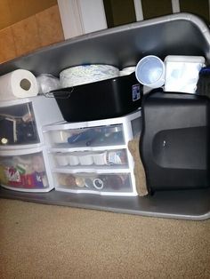 an organized kitchen counter with dishes and cups in the bottom drawer, next to a trash can