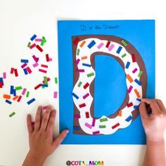 someone is making a paper letter with colored sprinkles