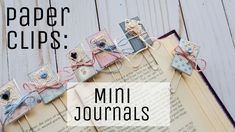 an open book sitting on top of a wooden table next to some scissors and paper clips