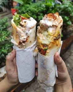 two burritos are being held up to the camera