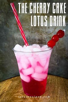 a cup filled with ice and cherries on top of a wooden table