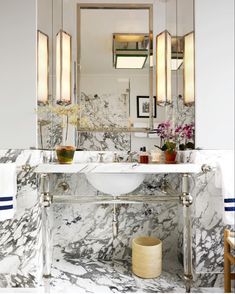 a bathroom with marble walls and flooring, two sinks and mirrors on the wall