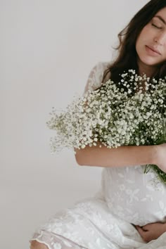 a woman in a white dress holding a bouquet of baby's breathflowers