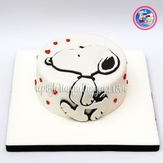 a white cake decorated with a snoopy dog on it's side and red hearts