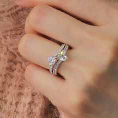 a woman's hand holding a ring with two diamonds on it and the middle finger