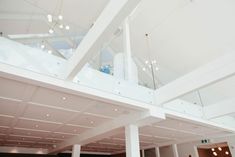 the inside of a large building with white walls and ceiling lights hanging from it's sides