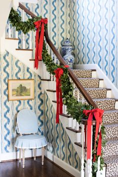 christmas decorations on the banisters and stairs in a house with blue wallpaper