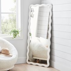 a white chair sitting next to a large mirror in a room with wooden floors and walls