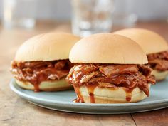 three pulled pork sandwiches sitting on top of a blue plate