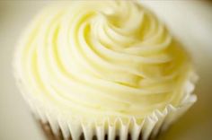 a cupcake with white frosting sitting on top of a table