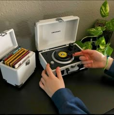 a child playing with an old fashioned record player on a table in front of a plant