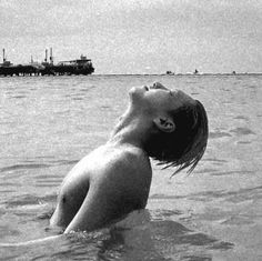 a woman in the water looking up at a boat