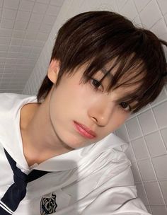 a young man wearing a white shirt and blue tie posing for a photo in front of a tiled wall