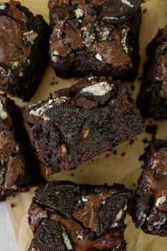 chocolate brownies with oreo cookies and white frosting on top, sitting on a piece of parchment paper