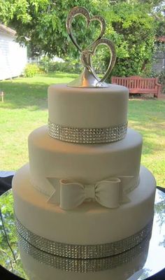 a white wedding cake with two hearts on top