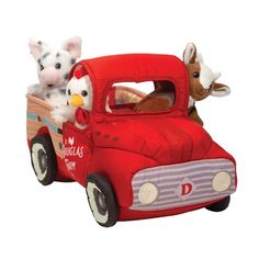 two stuffed animals riding in the back of a red truck