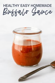 a jar filled with sauce next to a spoon