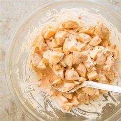 a glass bowl filled with food sitting on top of a white counter next to a silver spoon