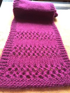 a purple knitted scarf sitting on top of a table