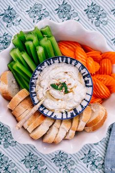 a bowl filled with hummus, celery and carrots next to bread