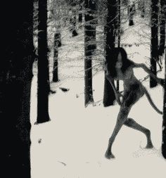 a woman is running through the woods in the snow while holding onto an object with one hand