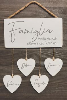 four white hearts hanging from a rope on a wooden wall with the words famiglia above them