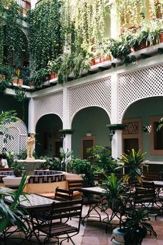 an outdoor courtyard with tables, chairs and potted plants on the side of the building