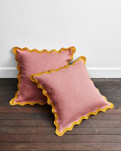 two pink pillows sitting on top of a wooden floor